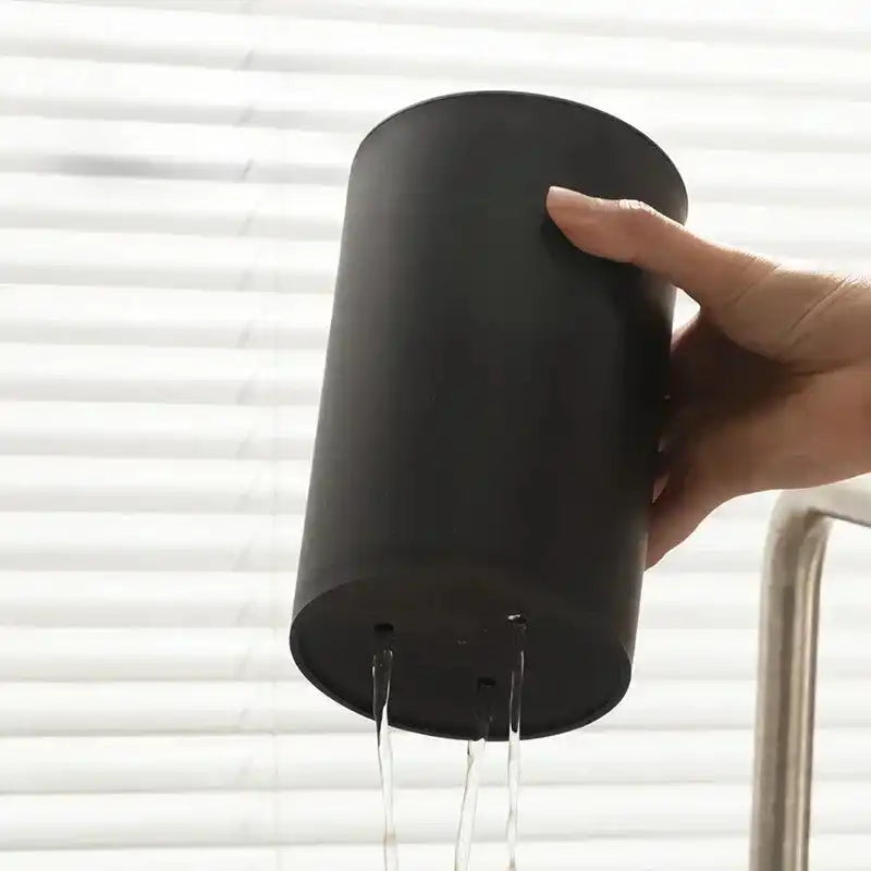 Drainable base of black kitchen knife holder with water flowing out, showcasing easy cleaning and maintenance feature.