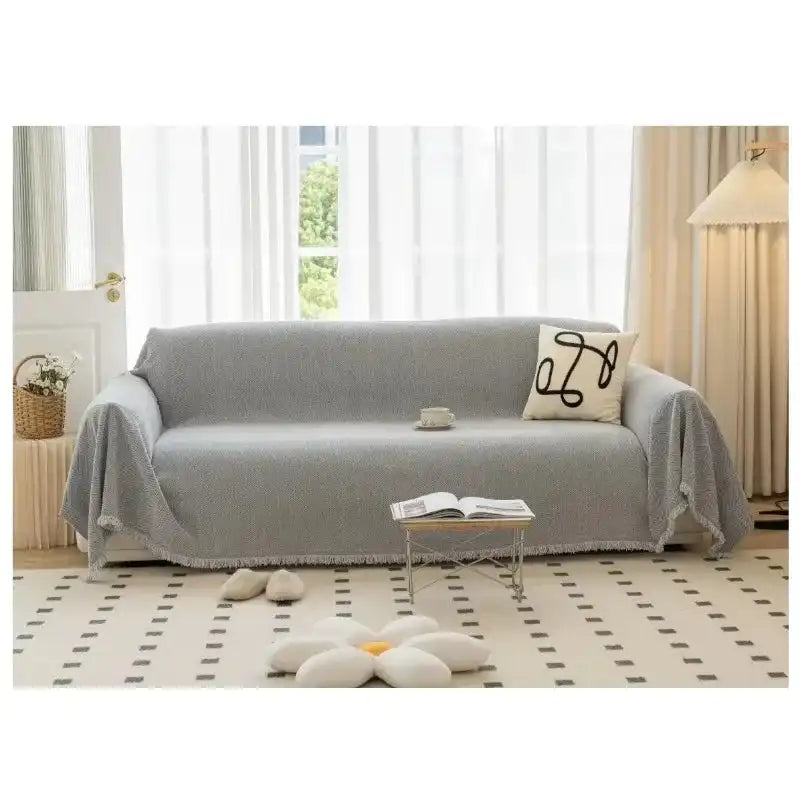 Gray solid sofa towel cover with tassel edges on a loveseat, featuring a non-slip and washable design for stylish living room decoration.