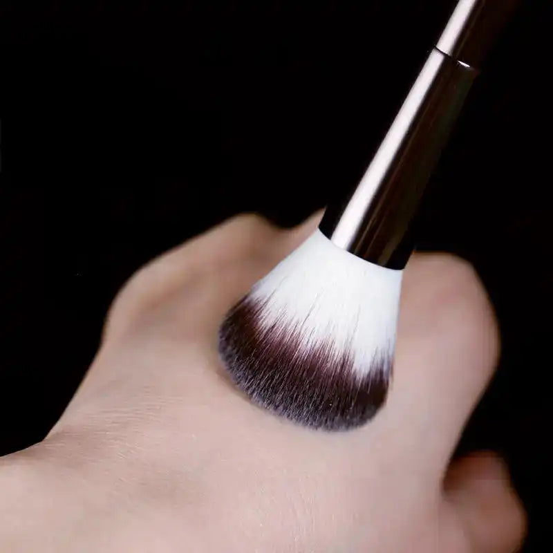 Soft nylon bristles of the double-head makeup brush gently pressed on skin, ideal for blush and powder blending.