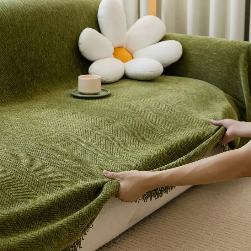 Green solid non-slip sofa towel cover with breathable knit fabric and tassel edge, ideal for L-shaped or modular sofas in living rooms.