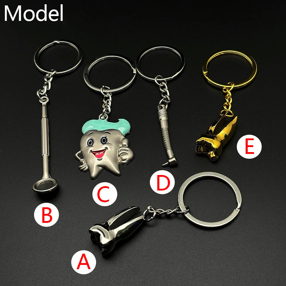 Set of five dentist-themed metal keychains labeled A to E, featuring dental tools and a smiling cartoon tooth charm with teal hair.