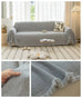 Gray sofa towel cover with herringbone knit pattern and tassel fringe, washable and non-slip for modern living room furniture protection.