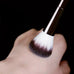 Soft nylon bristles of the double-head makeup brush gently pressed on skin, ideal for blush and powder blending.