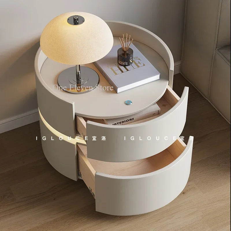 Modern white bedside table with drawers, table lamp, book, and decorative items in bedroom