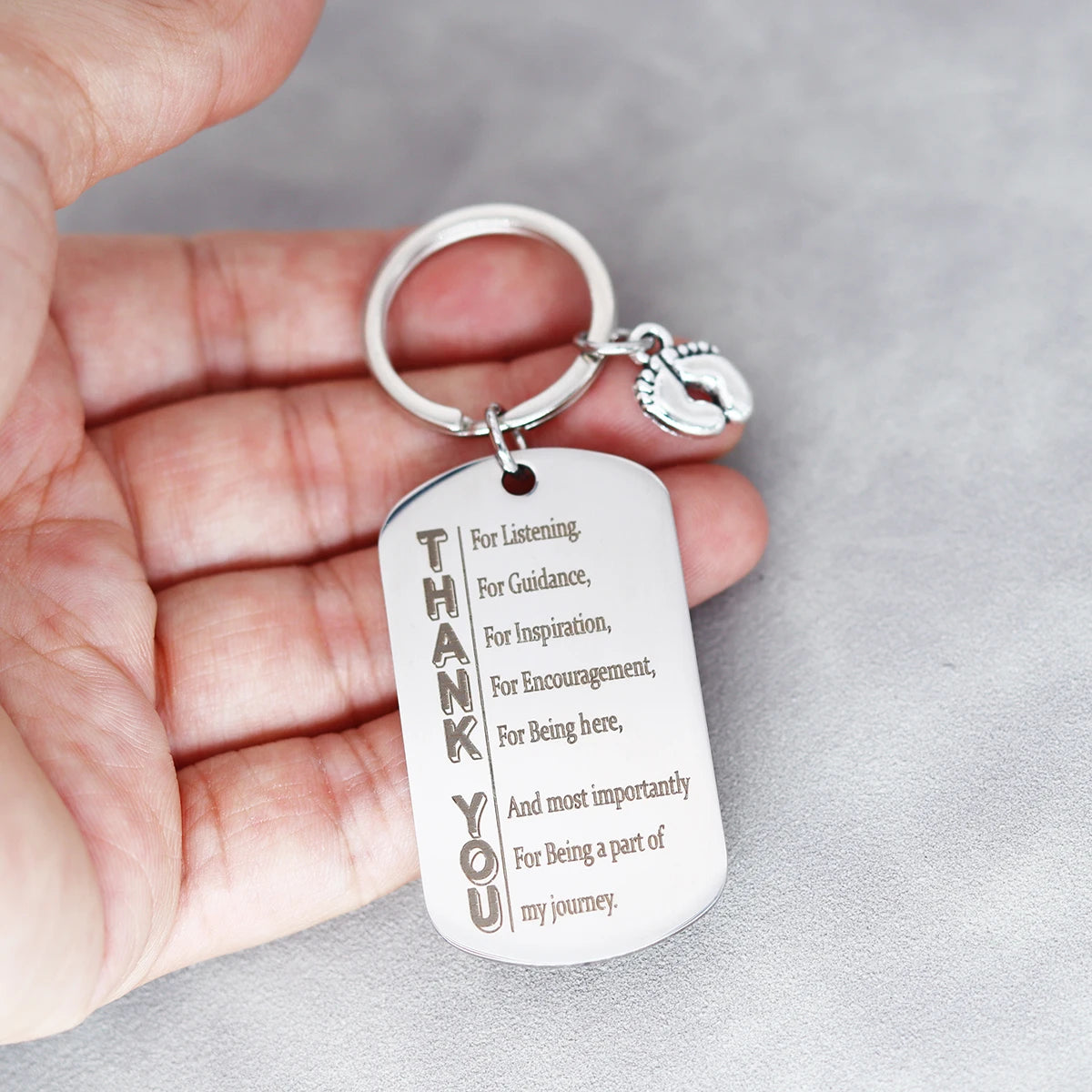 Unisex stainless steel Thank You keychain held in hand, featuring engraved appreciation message for support and encouragement.