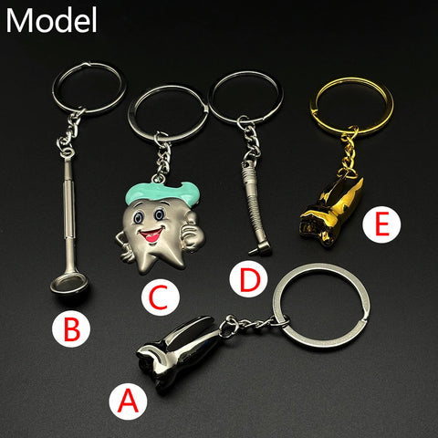 Set of five dentist-themed metal keychains labeled A to E, featuring dental tools and a smiling cartoon tooth charm with teal hair.